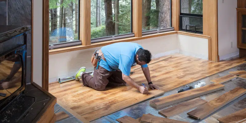 Professional hardwood floor installation showing skilled craftsman installing oak planks - hardwood floor installation costs